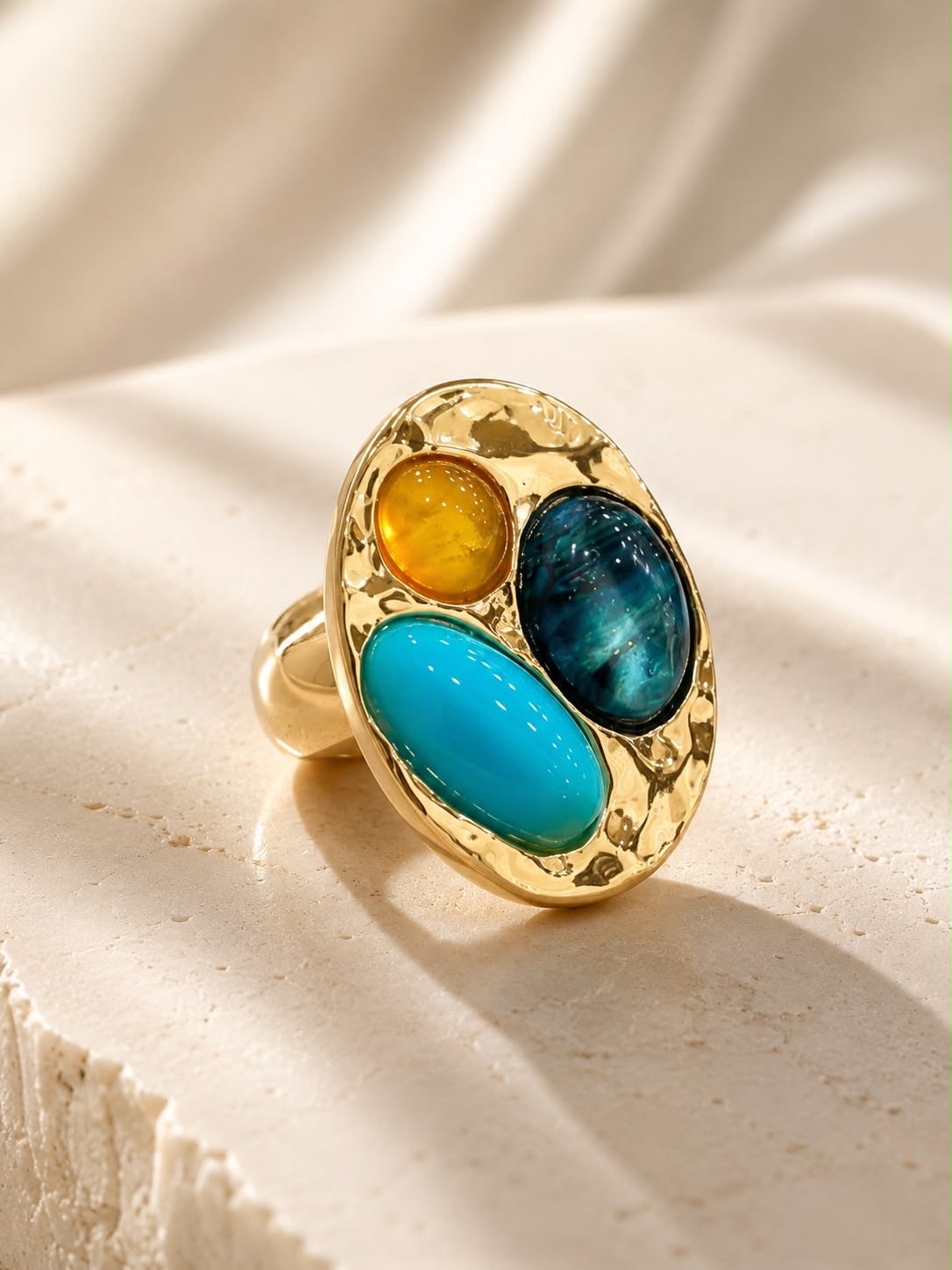Anillo dorado ovalado con tres piedras de color