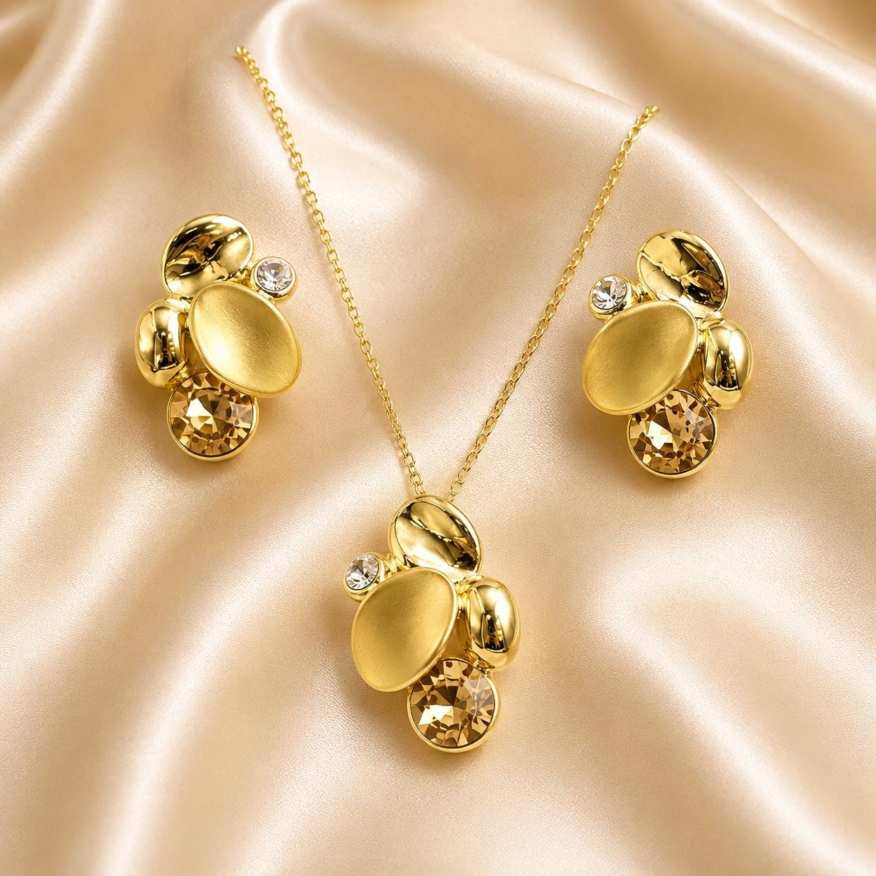 Set dorado de collar y aretes con formas ovaladas sobre tela satinada