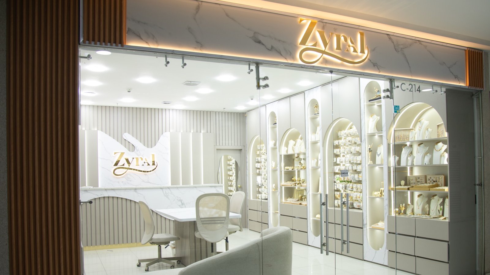 Fachada del showroom ZYRAL con el logo dorado iluminado y vitrinas de accesorios