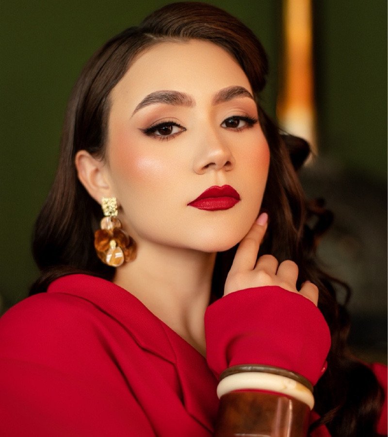 Retrato de mujer con aretes dorados y brazaletes, con chaqueta roja
